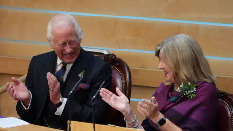 PA Media The King laughing and applauding with Presiding Officer Alison Johnstone