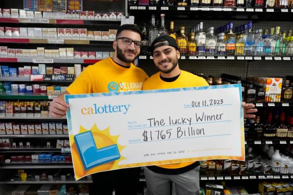 Jonathan Khalil, left, and Chris Khalil, sons of the store co-owners hold up the ceremonial check presented to the store on Thursday.