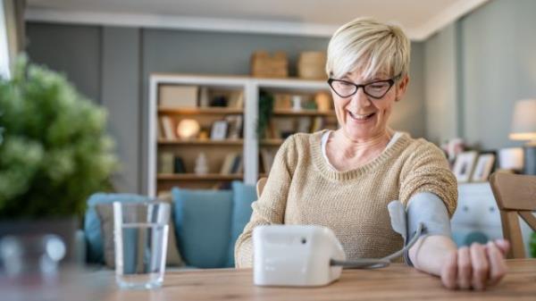 Happy senior woman checking her blood pressure levels at home