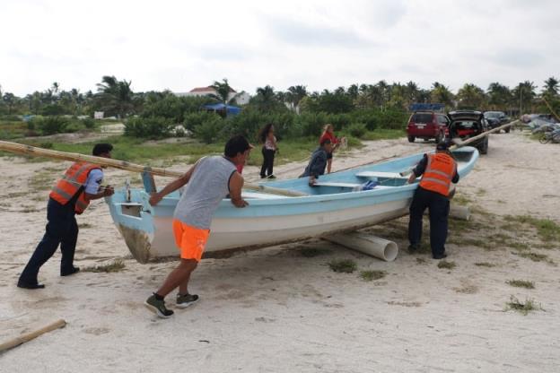 A group of people push a boat off a beach